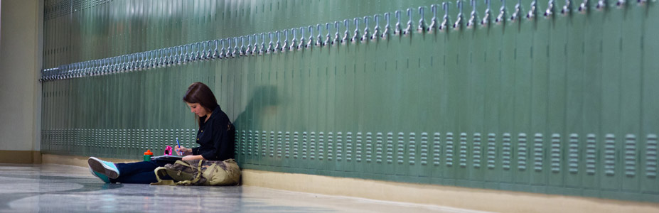 Undergraduate student studying on floor by lockers