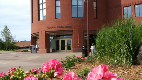 a photograph of the kathryn martin library. pink flowers are pictured in front of the library building. 