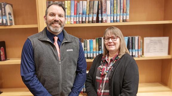 Adam Brisk and Kay Westergren stand in front of bookshelves