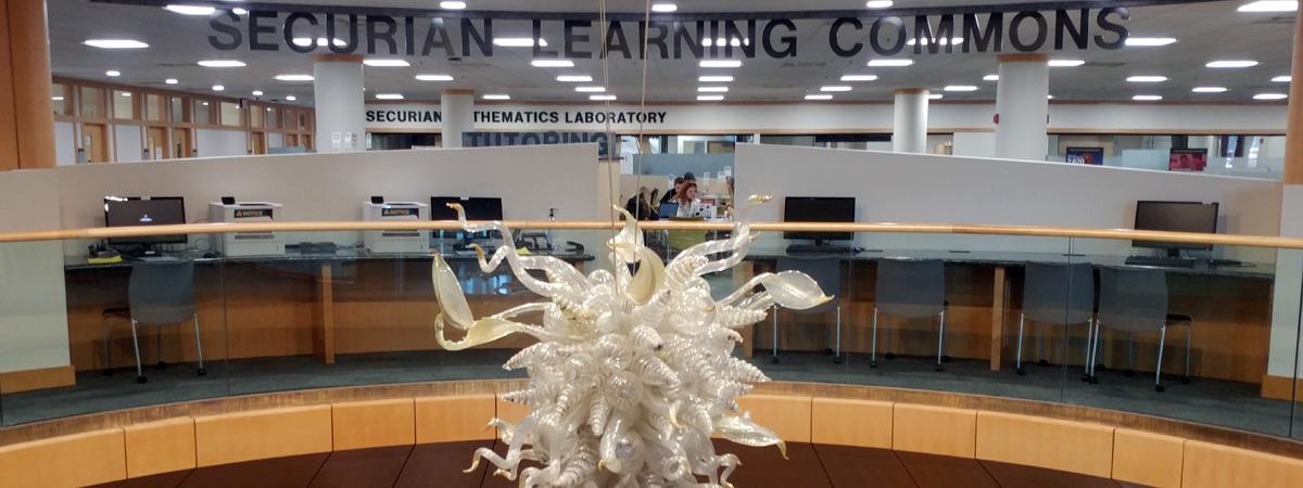 Securian Learning Commons sign with Chihuly glass sculpture in foreground, second floor.