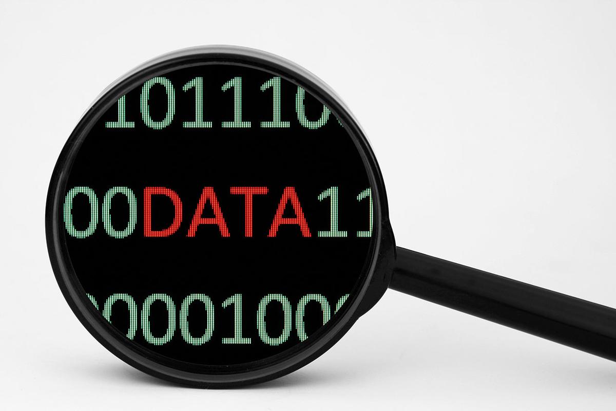 black Magnifying glass on white background, the glass is zooming in on text of binary code and the word "Data"