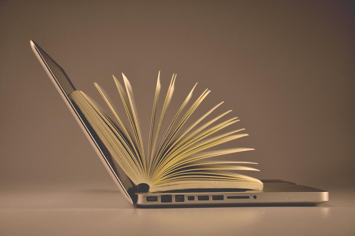 laptop computer and book with a plain background