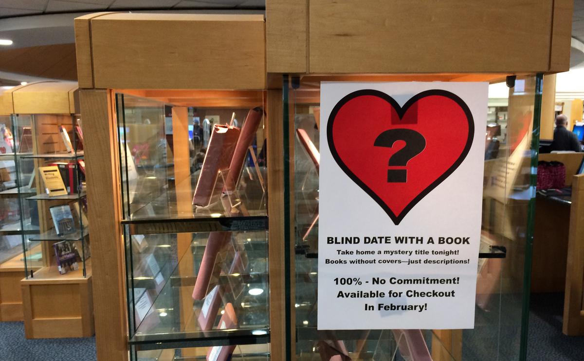 library display case showing books wrapped and sign with question mark inside heart 